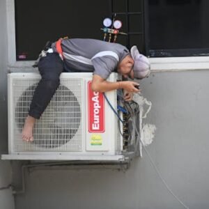 A technician skillfully repairing an outdoor air conditioning unit mounted on a building wall.