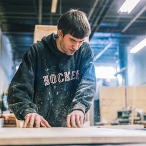 A committed carpenter sanding wood in a bustling workshop, showcasing precision and skill.