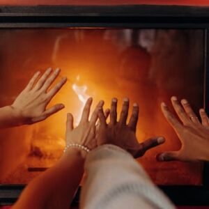 Close-up of hands warming by a cozy fireplace, radiating warmth and comfort.