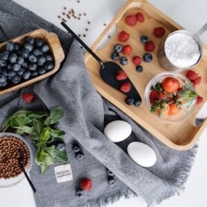 Creative flat lay showcasing a mix of berries, eggs, and baking ingredients on a textured fabric background.