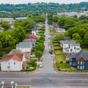 Aerial shot of a green suburban neighborhood with tree-lined streets and residential houses.