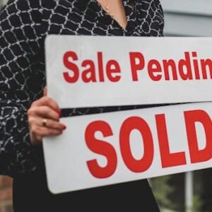 A businesswoman holding 'Sale Pending' and 'Sold' signs indicating a successful real estate transaction.